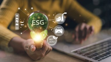 Sanal ekranda ESG ikonlu bir ampulü tutan iş kadını, ESG Çevre, Sosyal ve Kurumsal Yönetim kavramı
