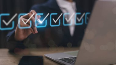 Kontrol listesi konsepti. Dizüstü bilgisayar kullanan bir iş adamı. Gelecekteki sanal arayüz ekranında işaretler işaretleniyor