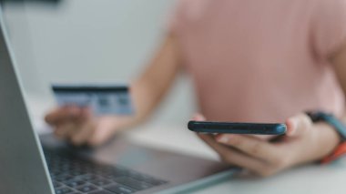 Kredi kartı tutan ve dizüstü bilgisayar kullanan eller. Çevrimiçi alışveriş ve çevrimiçi ödeme kavramları.
