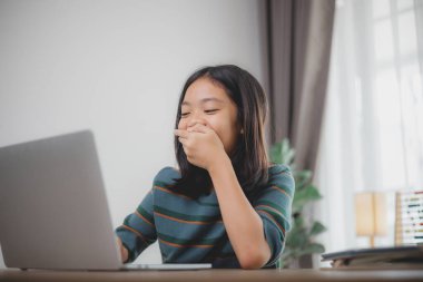 Genç bir kız önünde dizüstü bilgisayarla bir masada oturuyor. Muhtemelen ekranda gördüğü bir şey yüzünden gülüyor ve surat yapıyor. Sahne neşeli bir şekilde aktarılıyor.