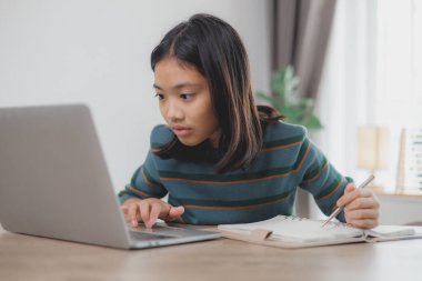 Masasında dizüstü bilgisayarı ve not defteri olan bir kız oturuyor. O, dizüstü bilgisayarda yazıyor ve deftere yazıyor. Sahne bir proje ya da ödev üzerinde çalıştığını gösteriyor.