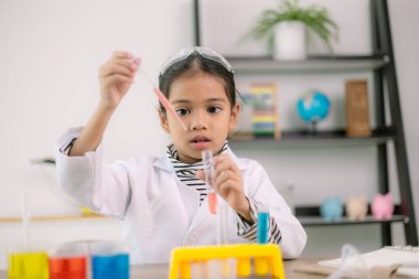 Asyalı kız öğrenci, test tüpü ile fen kimyası öğreniyor. Laboratuvarda deney yapıyor. Eğitim, bilim, kimya ve çocuk kavramları. Çocukların erken gelişimi.