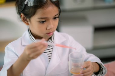 Asyalı kız öğrenci, test tüpü ile fen kimyası öğreniyor. Laboratuvarda deney yapıyor. Eğitim, bilim, kimya ve çocuk kavramları. Çocukların erken gelişimi.