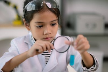 Asyalı kız öğrenci, test tüpü ile fen kimyası öğreniyor. Laboratuvarda deney yapıyor. Eğitim, bilim, kimya ve çocuk kavramları. Çocukların erken gelişimi.