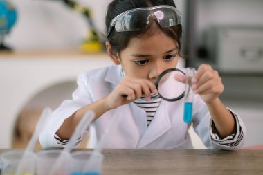 Asyalı kız öğrenci, test tüpü ile fen kimyası öğreniyor. Laboratuvarda deney yapıyor. Eğitim, bilim, kimya ve çocuk kavramları. Çocukların erken gelişimi.