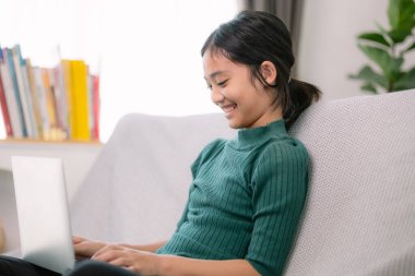 Asyalı genç kızlar rahat bir kanepede dizüstü bilgisayarda ödev yapıyorlar..