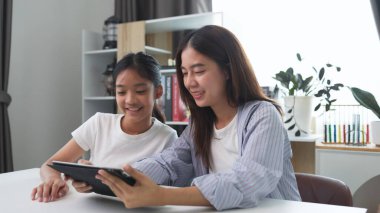 İki komik Asyalı kız gülüyor ve sosyal medya videolarını evde akıllı bir telefonla paylaşıyorlar.