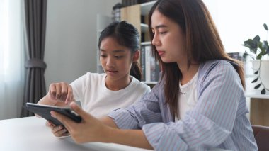 İki komik Asyalı kız gülüyor ve sosyal medya videolarını evde akıllı bir telefonla paylaşıyorlar.
