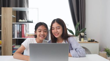 İki komik Asyalı kız gülüyor ve sosyal medya videolarını evde akıllı bir telefonla paylaşıyorlar.