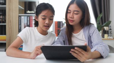 İki komik Asyalı kız gülüyor ve sosyal medya videolarını evde akıllı bir telefonla paylaşıyorlar.