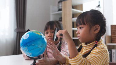 İki küçük Asyalı kız dünyayı kurtarma konseptini öğreniyor ve evde çocuk eğitimi için oyun aktivitesi yaparak öğreniyor..