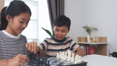 Asyalı küçük oğlan ve Asyalı küçük kız evde satranç oynuyorlar. Satranç oynayan çocuklar