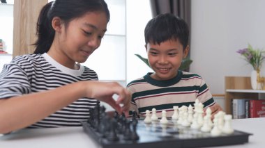 Asyalı küçük oğlan ve Asyalı küçük kız evde satranç oynuyorlar. Satranç oynayan çocuklar