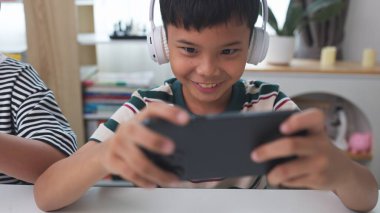 Asyalı çocuklar evde eğlenmek için arkadaşlarıyla çevrimiçi video oyunları oynuyorlar..