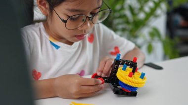 BTMM eğitim konsepti. Asyalı ev okulu kızları internetten ders alıyorlar ve BTMM oyuncakları yapmak için heyecanlılar. Çocukların kavramları için matematik mühendisliği bilgisayar kodu..