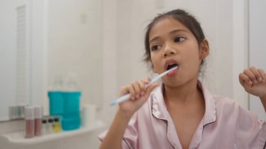 Sabah rutini, gülümseyen mutlu Asyalı kızlar diş fırçasıyla dişlerini fırçalıyorlar. Küçük kızların diş sağlığı, tıbbi bakım..