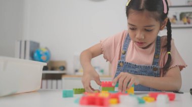 Çocuk renkli oyuncak bloklarıyla oynuyor. Çocuklar oynar. Küçük kızlar oyuncaklardan bir kule yapıyorlar. Bebekler ve yeni yürümeye başlayanlar için eğitici bir oyun. Çocuklar oyuncak ev yapar.