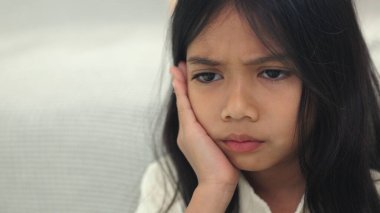 Güzel bir kız çocuğu diş ağrısı ya da diş hastalığından dolayı acı dolu bir ifadeyle ağzına dokunuyor. Dişçi konsepti.