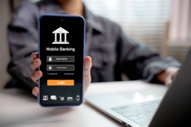 Mobil bankacılık giriş ekranı olan akıllı telefonu elinde tutan kişi. Mobil cihazda dijital finans, çevrimiçi bankacılık, güvenli işlem, fintech ve modern finans teknolojisi kavramı.