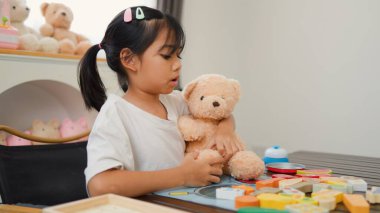 Asyalı kız evde oyuncak ayı ve oyuncak yemekle oynuyormuş gibi yapıyor. Yaratıcılığı, sosyal becerileri ve erken çocukluk gelişimini yaratıcı öğrenme faaliyetleri yoluyla teşvik etmek.