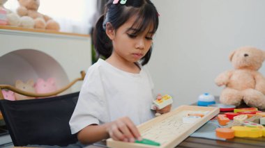 Evde renkli bulmaca bloklarıyla oynayan Asyalı kız, yaratıcı ve dokunsal öğrenme faaliyetleri yoluyla erken çocukluk eğitimi, beyin gelişimi ve bilişsel becerileri teşvik ediyor..