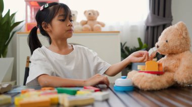 Asyalı kız evde oyuncak ayı ve oyuncak yemekle oynuyormuş gibi yapıyor. Yaratıcılığı, sosyal becerileri ve erken çocukluk gelişimini yaratıcı öğrenme faaliyetleri yoluyla teşvik etmek.