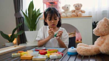 Asyalı kız evde oyuncak ayı ve oyuncak yemekle oynuyormuş gibi yapıyor. Yaratıcılığı, sosyal becerileri ve erken çocukluk gelişimini yaratıcı öğrenme faaliyetleri yoluyla teşvik etmek.