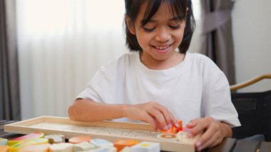 Evde renkli bulmaca bloklarıyla oynayan Asyalı kız, yaratıcı ve dokunsal öğrenme faaliyetleri yoluyla erken çocukluk eğitimi, beyin gelişimi ve bilişsel becerileri teşvik ediyor..