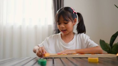 Evde renkli bulmaca bloklarıyla oynayan Asyalı kız, yaratıcı ve dokunsal öğrenme faaliyetleri yoluyla erken çocukluk eğitimi, beyin gelişimi ve bilişsel becerileri teşvik ediyor..