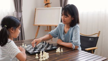 Evde satranç oynayan iki Asyalı kız çocuk gelişimi, eğitim ve kardeş kaynaşması kavramları için mükemmel, eğlenceli ve stratejik düşüncelerini ifade ediyorlar..