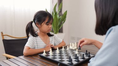 Evde satranç oynayan iki Asyalı kız kardeş, beyin becerilerini geliştirmek, mantıklı düşünmek, ve eğlenceli stratejik oyunlarla iç mekanda öğrenme ortamında bağ kurmak..