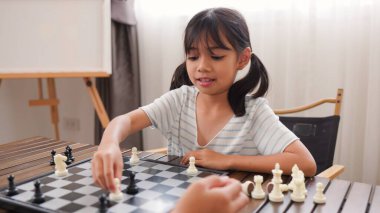 Evde satranç oynayan iki Asyalı kız kardeş, beyin becerilerini geliştirmek, mantıklı düşünmek, ve eğlenceli stratejik oyunlarla iç mekanda öğrenme ortamında bağ kurmak..