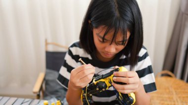 Asyalı kız evde robot kolu monte ediyor. BTMM eğitimini, kodlamayı, mühendisliği ve problem çözme becerilerini teşvik etmek. Geleceğin yenilikçileri ve genç mühendisleri için teknolojik eğitim..