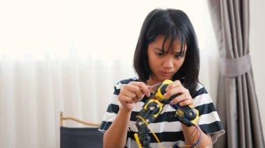 Asyalı kız evde robot kolu monte ediyor. BTMM eğitimini, kodlamayı, mühendisliği ve problem çözme becerilerini teşvik etmek. Geleceğin yenilikçileri ve genç mühendisleri için teknolojik eğitim..