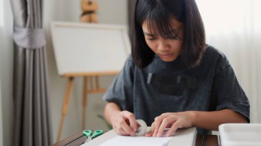 Evde yaratıcı DIY aktivitesi yapan Asyalı kızlar sanat malzemeleri, makas ve konsantrasyonla evde eğitim ortamında beceri ve hayal gücü geliştiriyorlar..