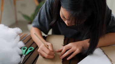 Evde yaratıcı DIY aktivitesi yapan Asyalı kızlar sanat malzemeleri, makas ve konsantrasyonla evde eğitim ortamında beceri ve hayal gücü geliştiriyorlar..