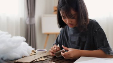 Evde yaratıcı DIY aktivitesi yapan Asyalı kızlar sanat malzemeleri, makas ve konsantrasyonla evde eğitim ortamında beceri ve hayal gücü geliştiriyorlar..