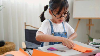 Asyalı kız evde pusula ve renkli bir kağıt kullanarak yaratıcılığı, motor becerileri ve ev okulunda eğlenceli öğrenmeyi destekleyen bir DIY zanaat projesi yapmaya odaklanmış..
