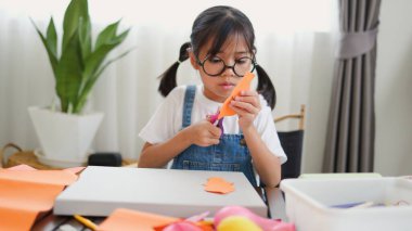 Asyalı kız evde pusula ve renkli bir kağıt kullanarak yaratıcılığı, motor becerileri ve ev okulunda eğlenceli öğrenmeyi destekleyen bir DIY zanaat projesi yapmaya odaklanmış..