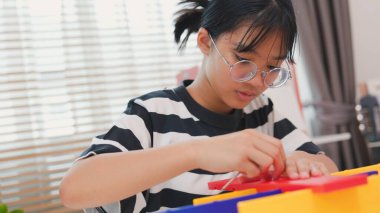 Asyalı kız, mekanik parçaları odaklanma ve kararlılıkla birleştirerek BTMM öğreniyor. Evde uygulamalı eğitim, çocuk mühendisliği, yaratıcılık ve bilim eğitimi kavramı.