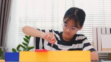 Asyalı kız, mekanik parçaları odaklanma ve kararlılıkla birleştirerek BTMM öğreniyor. Evde uygulamalı eğitim, çocuk mühendisliği, yaratıcılık ve bilim eğitimi kavramı.