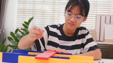 Asyalı kız, mekanik parçaları odaklanma ve kararlılıkla birleştirerek BTMM öğreniyor. Evde uygulamalı eğitim, çocuk mühendisliği, yaratıcılık ve bilim eğitimi kavramı.