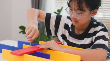 Asyalı kız, BTMM öğrenme etkinliğinin bir parçası olarak renkli bir plastik yapıyı tornavidayla birleştiriyor. Elle eğitim, çocuk mühendisliği, yaratıcılık ve sorun çözme kavramı.