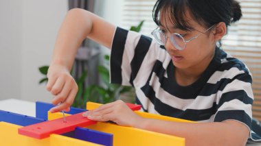 Asyalı kız, BTMM öğrenme etkinliğinin bir parçası olarak renkli bir plastik yapıyı tornavidayla birleştiriyor. Elle eğitim, çocuk mühendisliği, yaratıcılık ve sorun çözme kavramı.