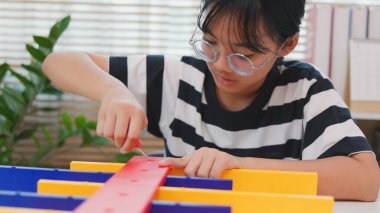 Asyalı kız, BTMM öğrenme etkinliğinin bir parçası olarak renkli bir plastik yapıyı tornavidayla birleştiriyor. Elle eğitim, çocuk mühendisliği, yaratıcılık ve sorun çözme kavramı.