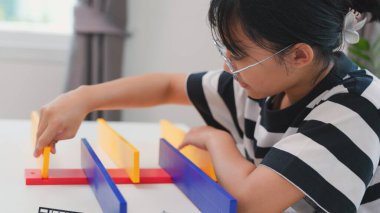 Asyalı kız, BTMM öğrenme etkinliğinin bir parçası olarak renkli bir plastik yapıyı tornavidayla birleştiriyor. Elle eğitim, çocuk mühendisliği, yaratıcılık ve sorun çözme kavramı.