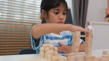Genç Asyalı kız tahta blokları istiflemeye, STEM öğrenimini, yaratıcılığı ve motor beceri gelişimini teşvik etmeye odaklandı. Erken eğitim kavramı, problem çözme ve bilişsel büyüme.