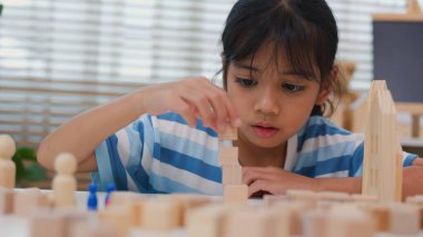 Genç Asyalı kız tahta blokları istiflemeye, STEM öğrenimini, yaratıcılığı ve motor beceri gelişimini teşvik etmeye odaklandı. Erken eğitim kavramı, problem çözme ve bilişsel büyüme.