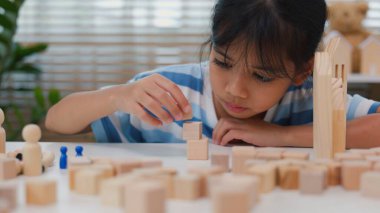 Genç Asyalı kız tahta blokları istiflemeye, STEM öğrenimini, yaratıcılığı ve motor beceri gelişimini teşvik etmeye odaklandı. Erken eğitim kavramı, problem çözme ve bilişsel büyüme.