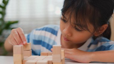 Genç Asyalı kız tahta blokları istiflemeye, STEM öğrenimini, yaratıcılığı ve motor beceri gelişimini teşvik etmeye odaklandı. Erken eğitim kavramı, problem çözme ve bilişsel büyüme.